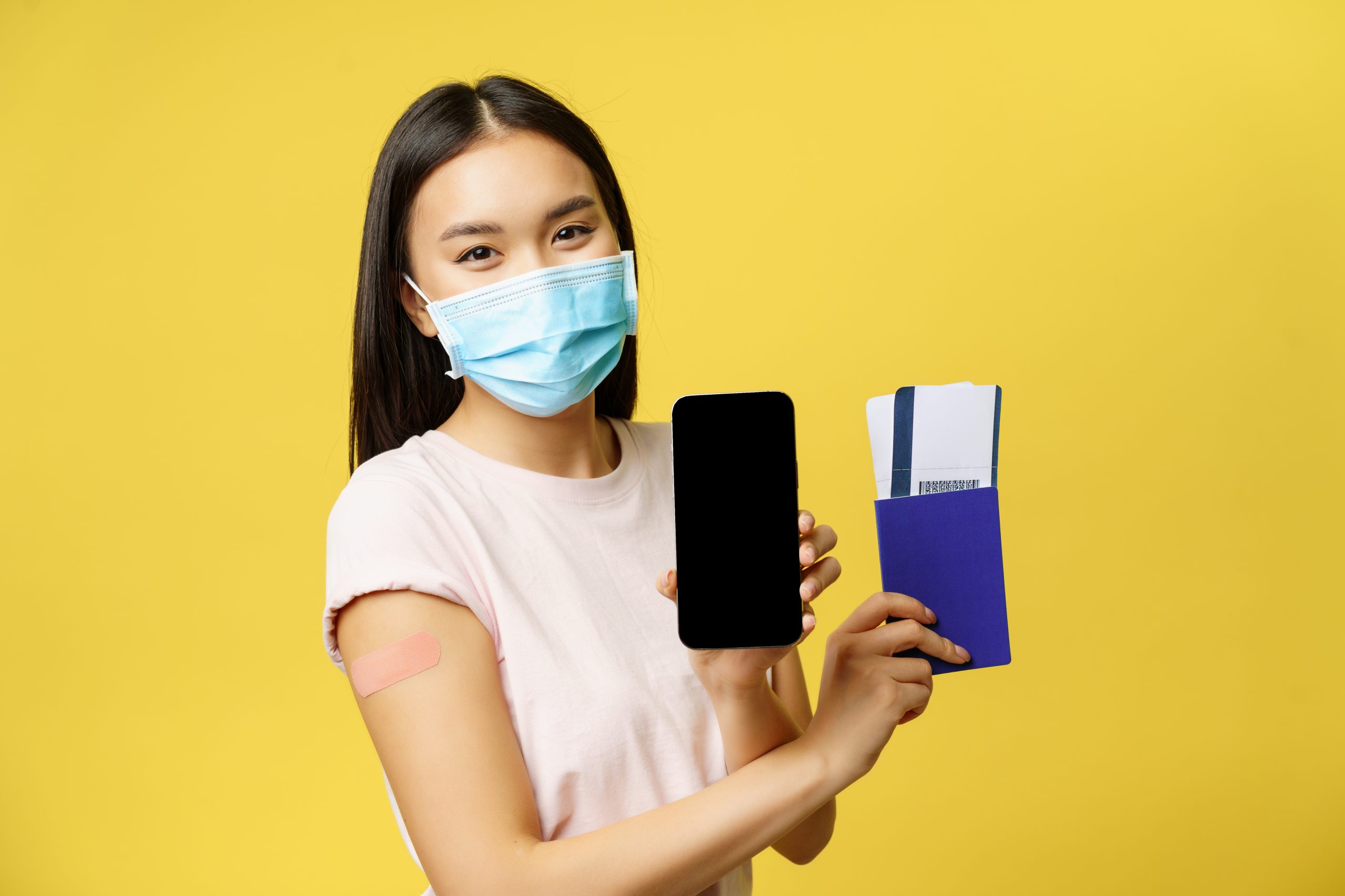 cara mengajukan visa ke malaysia untuk keperluan wisata medis. seorang wanita memakai masker sambil menunjukkan tiket dan paspor untuk ke luar negeri